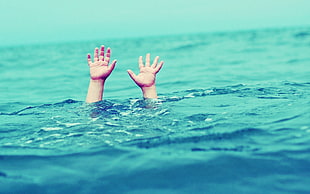 person drowning underwater while hands are above water
